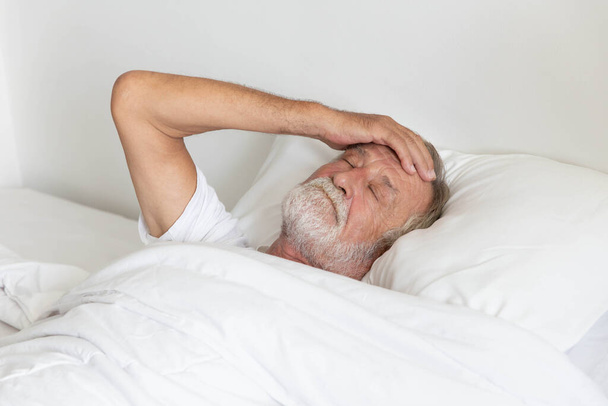 Worried senior retirement man lying awake in his bed - Φωτογραφία, εικόνα