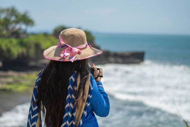 Yksin matkustava nainen sinisessä puvussa ottaa valokuvia merimaisemista horisontilla Balilla, Indonesiassa - Valokuva, kuva