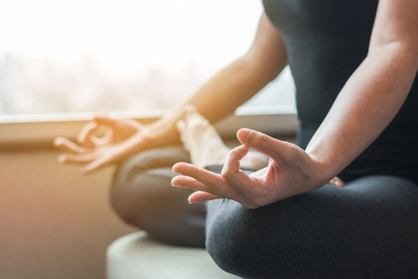 Yoga met vrouw persoon in lotus poseren mediteren in stilte sportschool klas of huis indoor in de ochtend - Foto, afbeelding