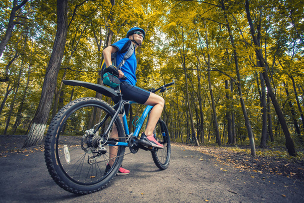 woman cyclist rides mountain bike forest trails. - 写真・画像