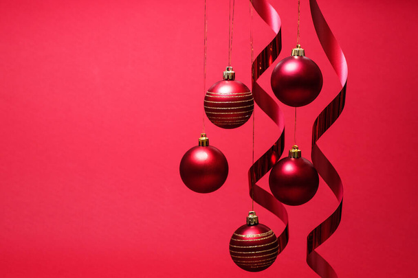 Balles et rubans de Noël suspendus. Composition Nouvel An sur fond rouge. - Photo, image
