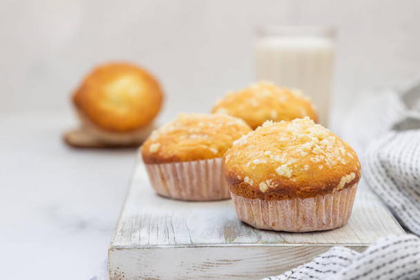 Vanilla muffins and muffins with streusel in paper cups with a glass of milk. Breakfast or snack for children. - Foto, Bild