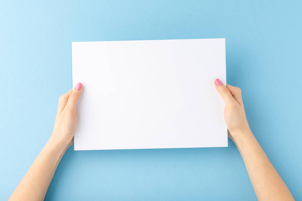 Young female hands showing empty white paper sheet on blue background. Mockup - Photo, Image