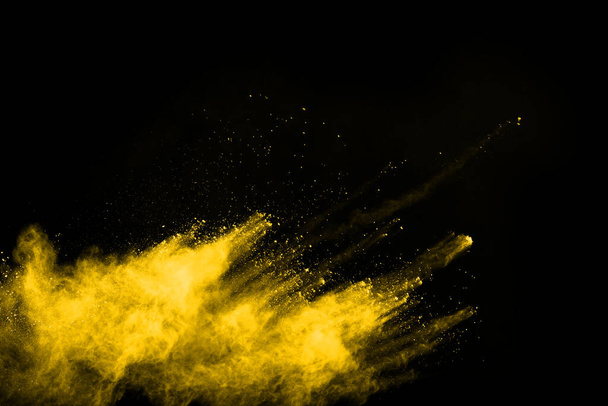 黒い背景に隔離された黄色の塵爆発の凍結運動. - 写真・画像