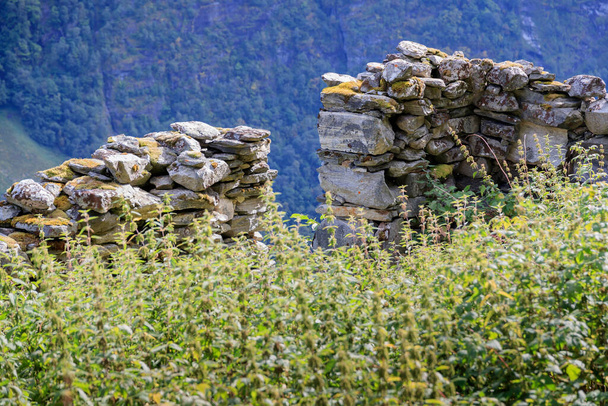 GEIRANGER, NORUEGA - 2017 SEPTIEMBRE 03. Antiguo muro de piedra abandonado de una granja Knivsflaa en la montaña Geiranger. - Foto, Imagen