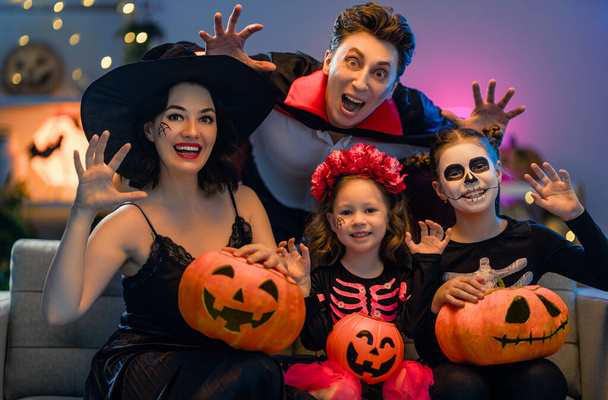 Mother, father and their kids having fun at home. Happy family celebrating Halloween. People wearing carnival costumes and makeup. - Photo, Image