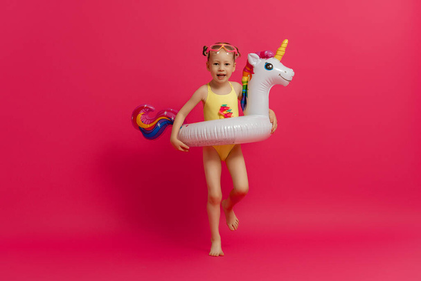 Happy child wearing swimsuit. Girl with swimming ring flamingo. Kid on a colored pink background. - Fotografie, Obrázek