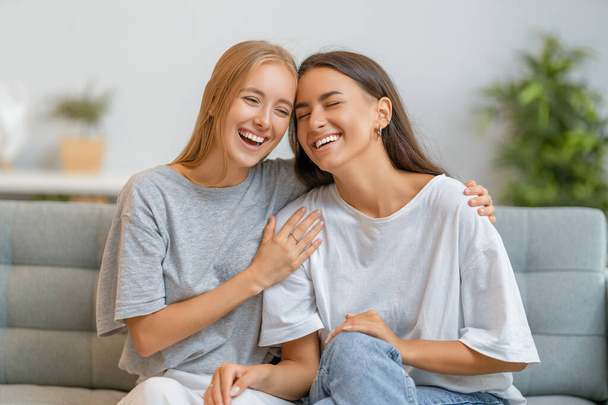 Portrait of two cheerful young women hugging at home. - Foto, afbeelding