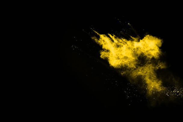 黒い背景に隔離された黄色の塵爆発の凍結運動. - 写真・画像