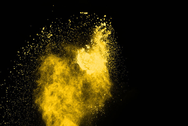 Παγωμένη κίνηση της έκρηξης κίτρινης σκόνης που απομονώνεται σε μαύρο φόντο. - Φωτογραφία, εικόνα
