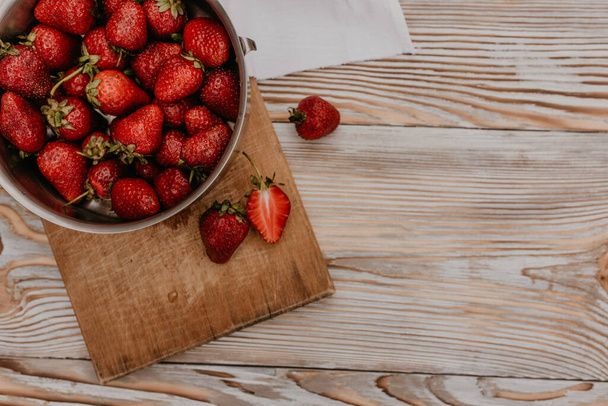 scattered juicy fresh red strawberries on the table with vintage plank. mint leaf. drops and splashes of spilled milk. vegetable cutting board. High quality photo - Fotografie, Obrázek