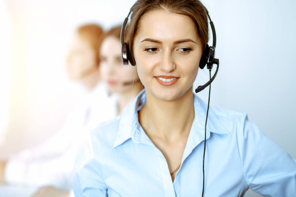Call center operators. Focus on beautiful business woman in headset. - Фото, изображение