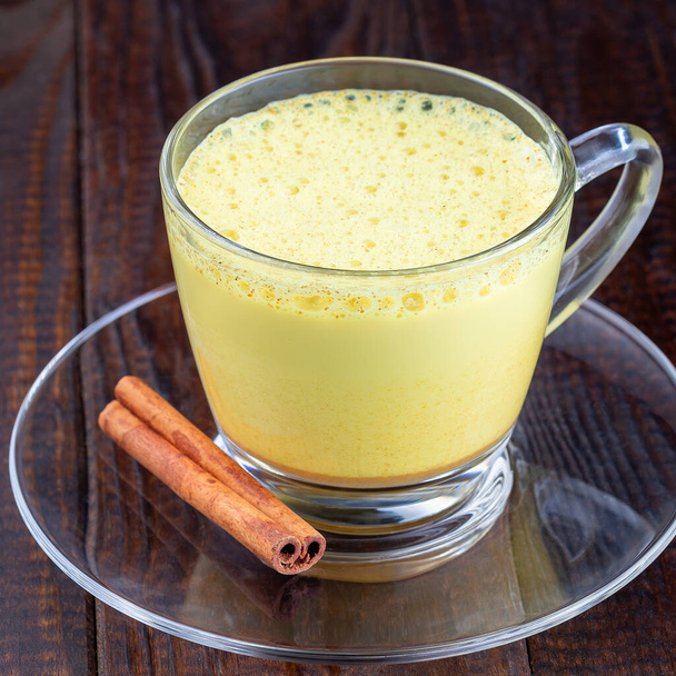 Moon milk with turmeric in a glass cup, square format, closeup - Фото, зображення
