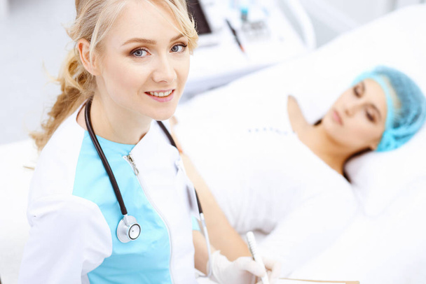 Female doctor and young woman patient in hospital. Physicians examine girl lying at the bed, view from above. Medical help and insurance in health care, best treatment and medicine concept - Zdjęcie, obraz