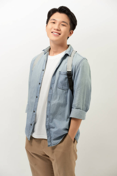 Handsome asian man with backpack smiling standing against white wall - Foto, imagen