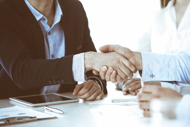 Business people shaking hands at meeting or negotiation, close-up. Group of unknown businessmen and women in modern office. Teamwork, partnership and handshake concept. - Фото, изображение