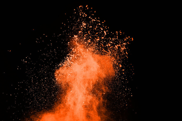Остановить движение взрывающегося оранжевого порошка, изолированного на черном фоне. Абстрактная конструкция облака красной пыли. - Фото, изображение