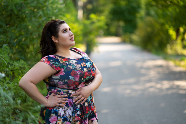 Plus size fashion model in floral dress outdoors, beautiful fat woman with beauty makeup and hairstyle, body positive concept - Foto, Imagen
