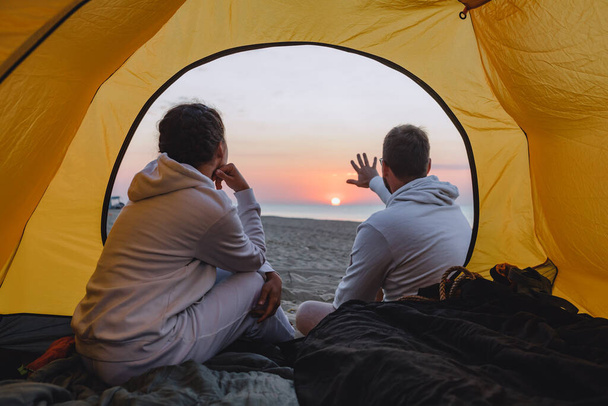 couple sitting in camping tent looking at sunset. togetherness - 写真・画像