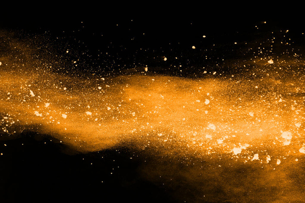 Freeze motion of yellow dust explosion isolated on black background. - Foto, afbeelding