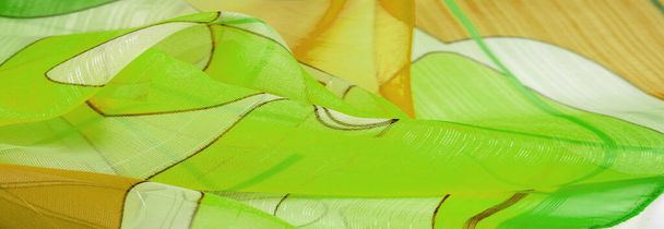 Η υφή του φόντου είναι ένα οργανικό σχέδιο - ένα ελαφρύ διαφανές ύφασμα από εκλεκτά πλεκτά, παρόμοιο με ένα πέπλο από λεπτό μετάξι βισκόζης. πράσινο λευκό κίτρινο γκρι γεωμετρικά χρώματα - Φωτογραφία, εικόνα