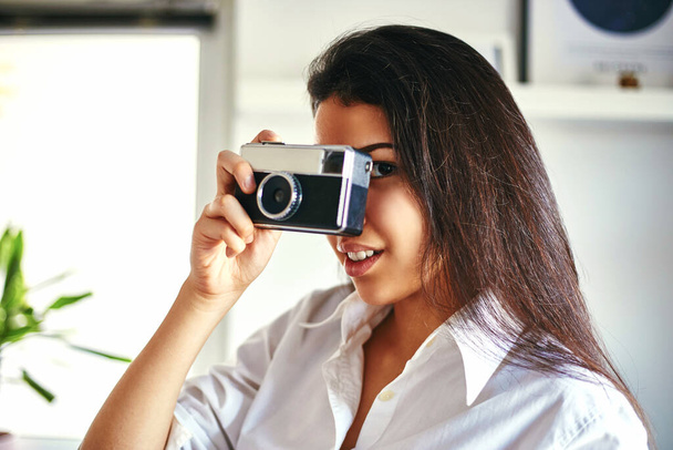 Trendy vrouw poseren met een retro film camera in haar kamer. Schoonheids- / modeconcept. - Foto, afbeelding