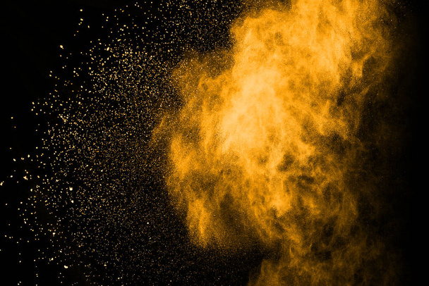 Congelar el movimiento de la explosión de polvo amarillo aislado sobre fondo negro. - Foto, Imagen