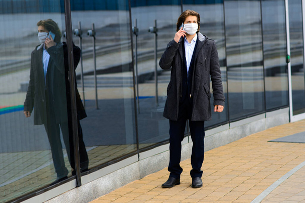 Junger Mann mit medizinischer Maske draußen, kein Geld, Armut, Not. Quarantäne, Isolation. - Foto, Bild