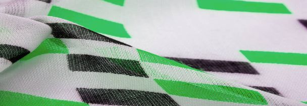Texture. Contexte. Un modèle. Tissu en soie blanche aux formes losanges géométriques vertes et noires. - Photo, image