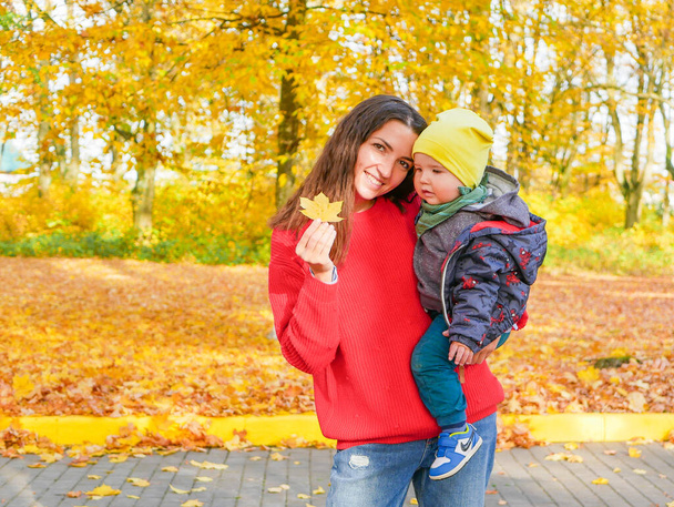 молода дівчина з дитиною на тлі опалого жовтого листя в парку. Високоякісна фотографія
 - Фото, зображення