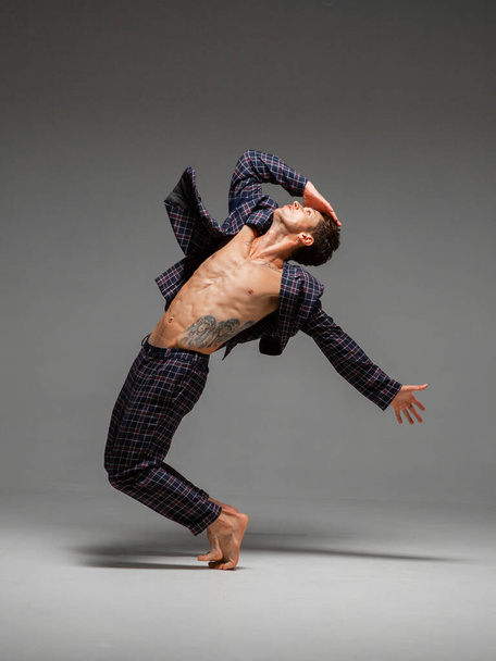 Handsome young guy dancer in suit and barefoot dancing expressive dance. Dance school poster. Body with tattoo - Foto, Imagen