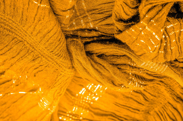 De textuur van de achtergrond patroon, ornament decor, goudgeel golfstof, weefsel met parallelle of diagonale plooien van gekartelde plooien; producten van een dergelijke stof. - Foto, afbeelding