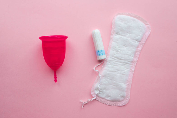 Menstrual cup and disposable pad and tampon. Reusable menstrual cup is an alternative to disposable tampons. Flat lay on pink background. Zero waste concept. Caring for the environment. Women Health. - Photo, image