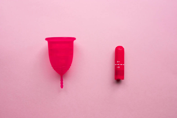 Menstrual cup and tampons. Reusable menstrual cup is an alternative to disposable tampons. Flat lay on pink background. Zero waste concept. Caring for the environment. Women Health. - Фото, изображение