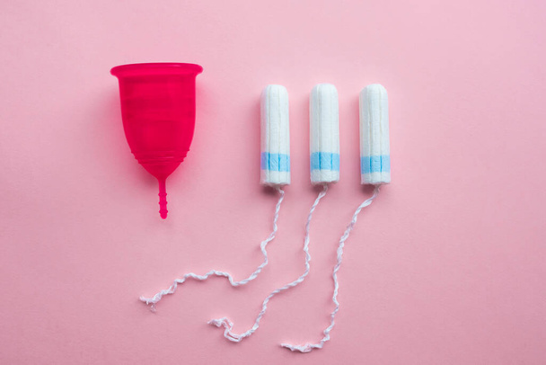 Menstrual cup and tampons. Reusable menstrual cup is an alternative to disposable tampons. Flat lay on pink background. Zero waste concept. Caring for the environment. Women Health. - Foto, Imagen