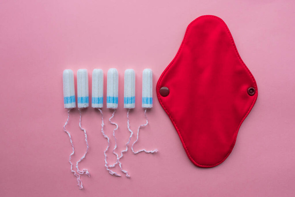 Reusable Cloth Sanitary Menstrual Pad and disposable tampon. Flat lay on pink background. Zero waste concept. Caring for the environment. Women Health. Conscious consumption. - 写真・画像