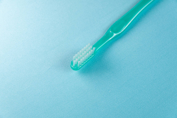 Πράσινη οδοντόβουρτσα στο μπλε φόντο - Φωτογραφία, εικόνα