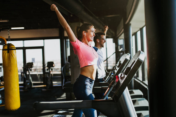 Young fit man and woman running on treadmill in modern fitness gym. - Foto, Imagem