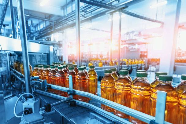 Заводской интерьер с производственной линией, конвейерная лента с соком в бутылках - Фото, изображение