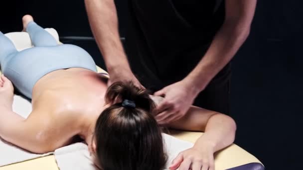 Masážní sezení v tmavém ateliéru - terapeutka masírující ženy zpět olejem - masírující ramenní kloub - Záběry, video