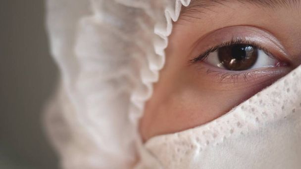 Nahaufnahme Porträt einer erfahrenen kaukasischen Chirurgin, Ärztin mit Maske, die bereit ist, in einem Krankenhaus oder einer Klinik zu arbeiten. Augen eines Arztes. Covid-19. Pandemie - Foto, Bild