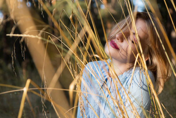 Європейська тендітна молода жінка, яка насолоджується заходом сонця на полі сухої трави. - Фото, зображення