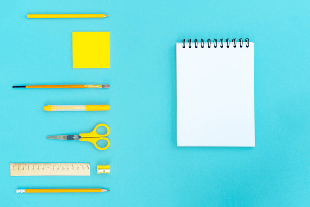 Open a blank notepad on the spiral and office and school supplies on blue background. Copy space, flat lay. Back to school concept. - Photo, Image