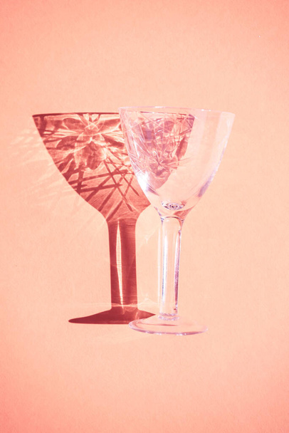 Beautiful abstract background wine glass light rays refracting, coral pastel color background, abstract design bright fun flat lay, light through glass shadow on colorful backdrop. - 写真・画像