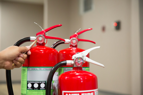 A tűzoltók ellenőrzik a vörös tűzoltó tartályok nyomásmérőjét az épületben. - Fotó, kép