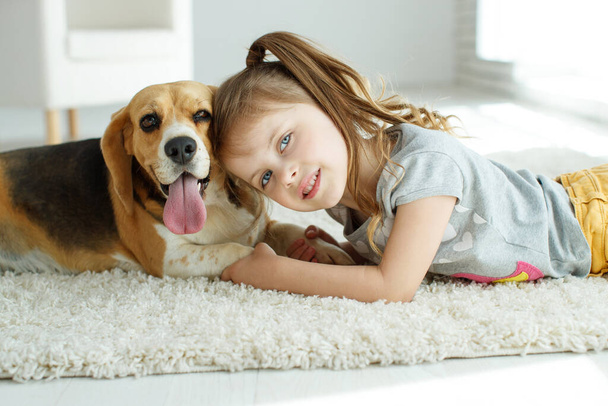 Маленькая девочка с собакой дома. - Фото, изображение