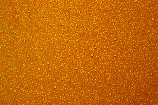 Wassertropfen auf dem orangefarbenen Hintergrund für kühle und frische Textur. - Foto, Bild