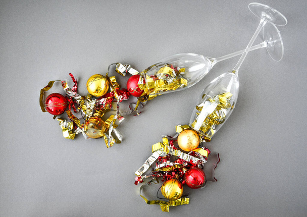 Két pohár pezsgő karácsonyi dekoráció fa labdák és konfetti szürke háttér, másolás helyet szöveg, Szilveszter és karácsonyi üdvözlőlap - Fotó, kép