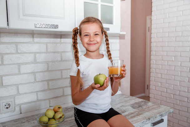 The girl keeps an apple and a glass of juice - Foto, Imagen
