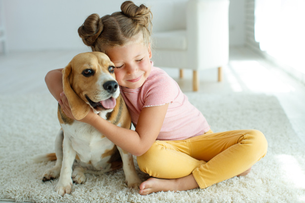 Gyerek kutyával. A kislány egy kutyával játszik otthon. Gyermek és állat. - Fotó, kép